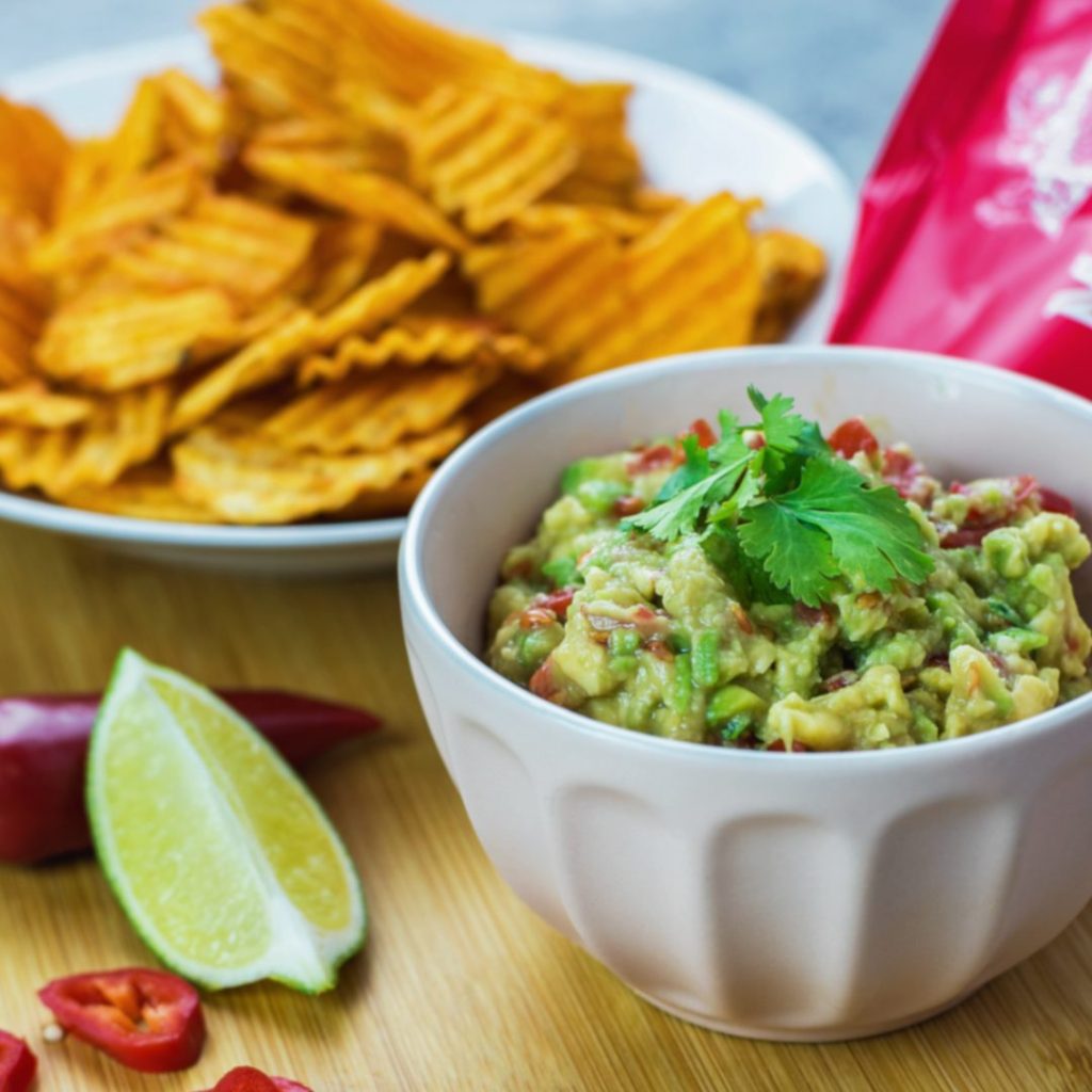 A plate of Mackies crisps, prawn cocktail flavour. Next to a bowl of fresh, homemade guacamole. The perfect pairing!