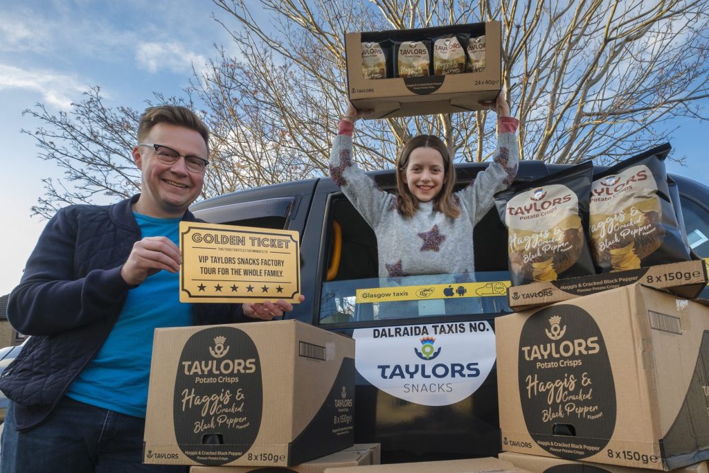 Greg Smith and Grace from Edinburgh, being presented with haggis crisps in a haggis taxi.